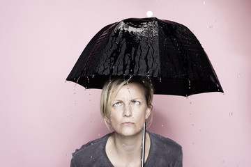 Woman under the wet umbrella in the rain in studio