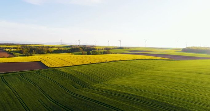 Aerial view of summer countryside with wind turbines and agricultural fields.