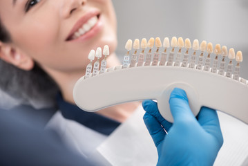 Odontologist arms showing teeth implants to patient