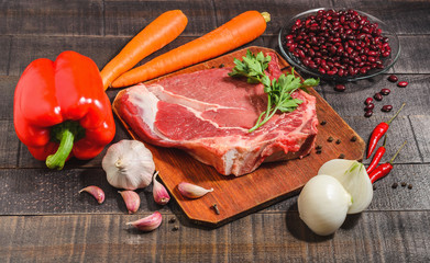 A raw piece of beef with pepper, carrots, beans and garlic