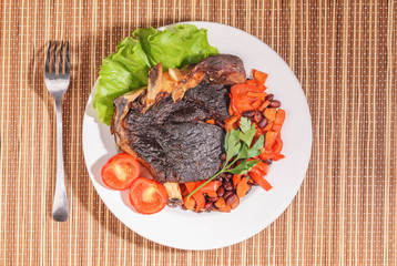 Fried beef steak with vegetables and beans on a plate