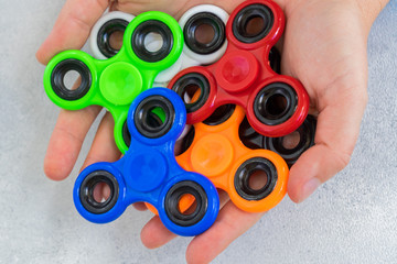 Mix of popular relaxing toy - fisget spinners - in someones open palms close up