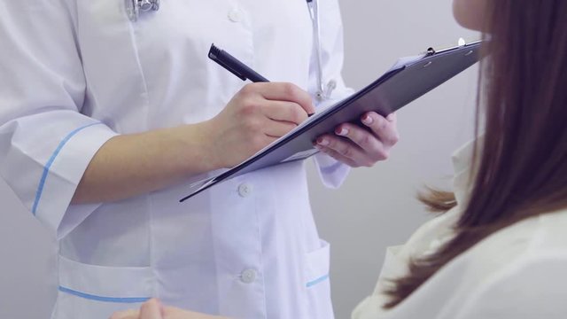 close up of patient and doctor taking notes in medical clinic