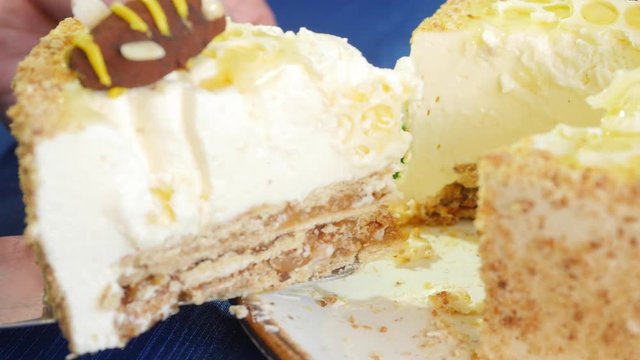 Female hands takes the piece of cake on the blade. Woman holding piece of cake on the blade. Piece of cake with honey cream on the blade. Close up