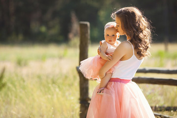 Young pretty mother with her little baby outdoors. Beautiful woman with her daughter on the nature. infant child with her parent