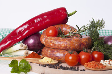 Fresh raw homemade sausage with spices and vegetables on a white background