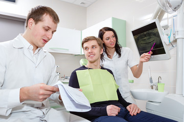 Male patient and dentist with assistant during check in at dental clinic
