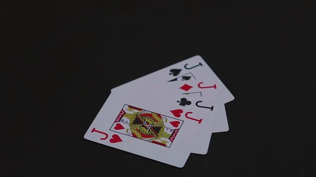 Man hand putting four jack poker cards on the black table