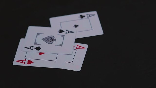 Four ace poker cards falling on the black table