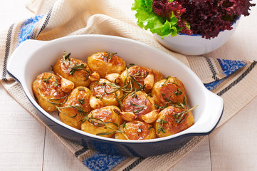 Roasted potatoes with garlic, thyme and rosemary in ceramic baking dish