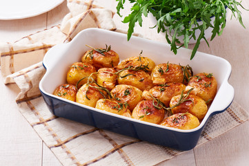 Roasted potatoes with garlic, thyme and rosemary in ceramic baking dish