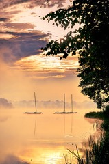 Plakat Morning foggy lake landscape. Boats on the lake.