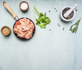 Asian cooking ingredients with fresh small shrimp in a small frying pan, herbs and pepper on wood blue background top view border, place for text
