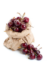 Ripe red cherry in a paper bag on a clean white background..