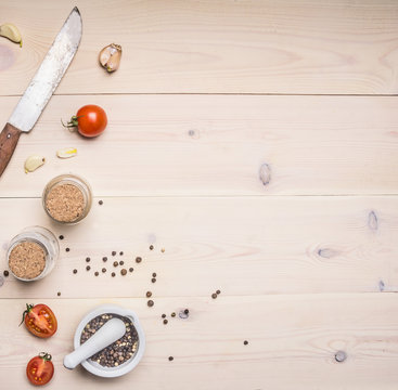 Ingredients for cooking  spices, knife, salt and pepper shakers, cherry tomatoes on a white wooden rustic background, space for text, Border