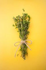 Bunch of fresh thyme on a bright yellow background..