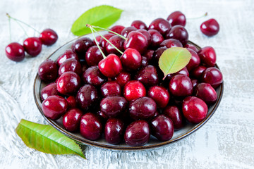Fresh cherry on plate on wooden blue background. fresh ripe cherries. sweet cherries