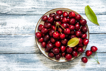 Fresh cherry on plate on wooden blue background. fresh ripe cherries. sweet cherries