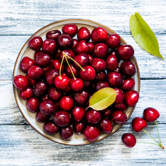 Fresh cherry on plate on wooden blue background. fresh ripe cherries. sweet cherries