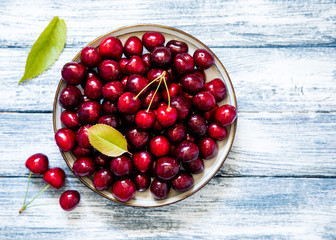 Fresh cherry on plate on wooden blue background. fresh ripe cherries. sweet cherries