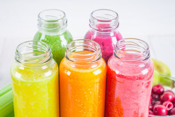 Fototapeta na wymiar Multicolored smoothies in bottles of mango, orange, banana, celery, berries, on a wooden table.