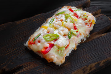 Part of delicious japanese rice pizza with shrimps served on rustic wooden table.Tasty appetizing food