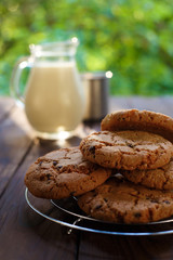 Delicious homemade cookies and jug of milk with metal mug on table. Natural organic drink with sweets ready for eating, tasty snack. Vertical picture.Home food, farming, countryside, healthy lifestyle