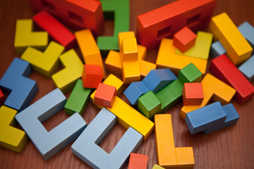 A wooden multicolored designer is chaotically scattered on the table. Wooden toy blocks, designer.