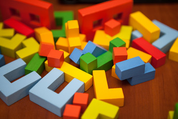 A wooden multicolored designer is chaotically scattered on the table. Wooden toy blocks, designer.