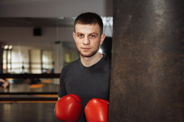 A young man is boxing in the hall. attentive sportsman in the boxing hall practicing boxing punches during training. strong man doing workout in the boxing hall
