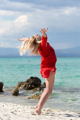 Outdoor portrait of young beautiful blonde woman jumping on the beach, fit sporty healthy body in bikini, woman enjoys wind, freedom, vacation, summertime fun concept.