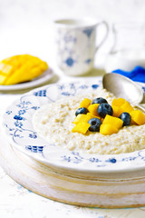 Oat porridge with mango and blueberry for a breakfast.