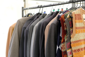 Obraz premium Selection of classic men's jackets and blazers and knitwear hanging on a rail