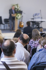 Fototapeta premium Business Concepts. Group of Adult Professionals Listening to the Lecturer Speaking on Stage During a Conference Indoors.