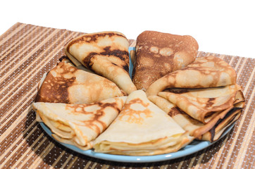 Russian traditional dishes - pancakes on a plate on a bamboo napkin