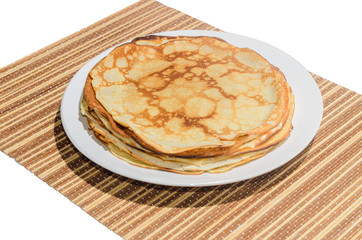 Russian traditional dishes - pancakes on a plate on a bamboo napkin