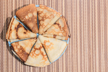 Russian traditional dishes - pancakes on a plate on a bamboo napkin