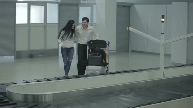 Young woman and man put their luggage to the trolley