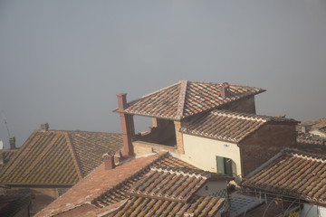 Tiled roofs of Siena on fog. Tuscany. Italy.