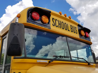 yellow school bus with cloud reflection in windshield © driftwood