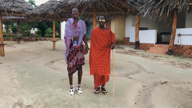 Two Masai people dances their national African dance on the Indian Ocean beach at sunset and bids farewell to the sun. Tanzania. Zanzibar. 4K.