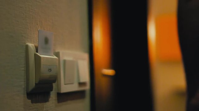 Traveler opens hotel door with a card key, steps inside the room