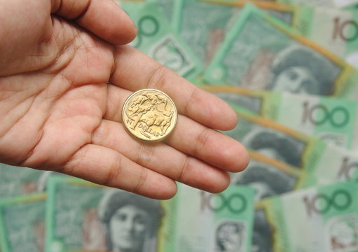 One Dollar Australia Golden Coin On Hand On One Hundred Banknote Background