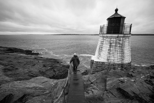Fototapeta A man walks down path towards Castle Hill Lighthouse in Newport, Rhode Island, on a dreary day, black and white