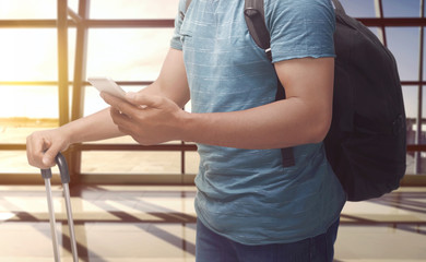 Man holding cellphone and suitcase
