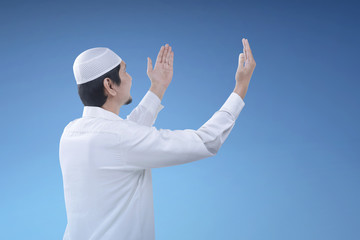 Religious muslim man raising hand and praying