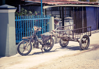 Fototapeta na wymiar Motobike in the Vietnamese village, adapted for cargo transportation. A picturesque village street. With toning