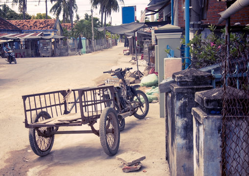 Motobike in the Vietnamese village, adapted for cargo transportation. A picturesque village street. With toning