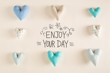 Enjoy Your Day message with blue heart cushions on a white paper background