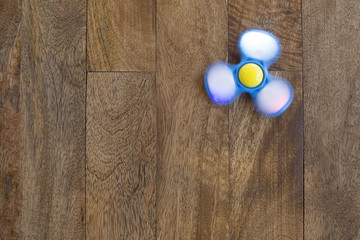 Play Fidget spinner spinning on wood background With Light